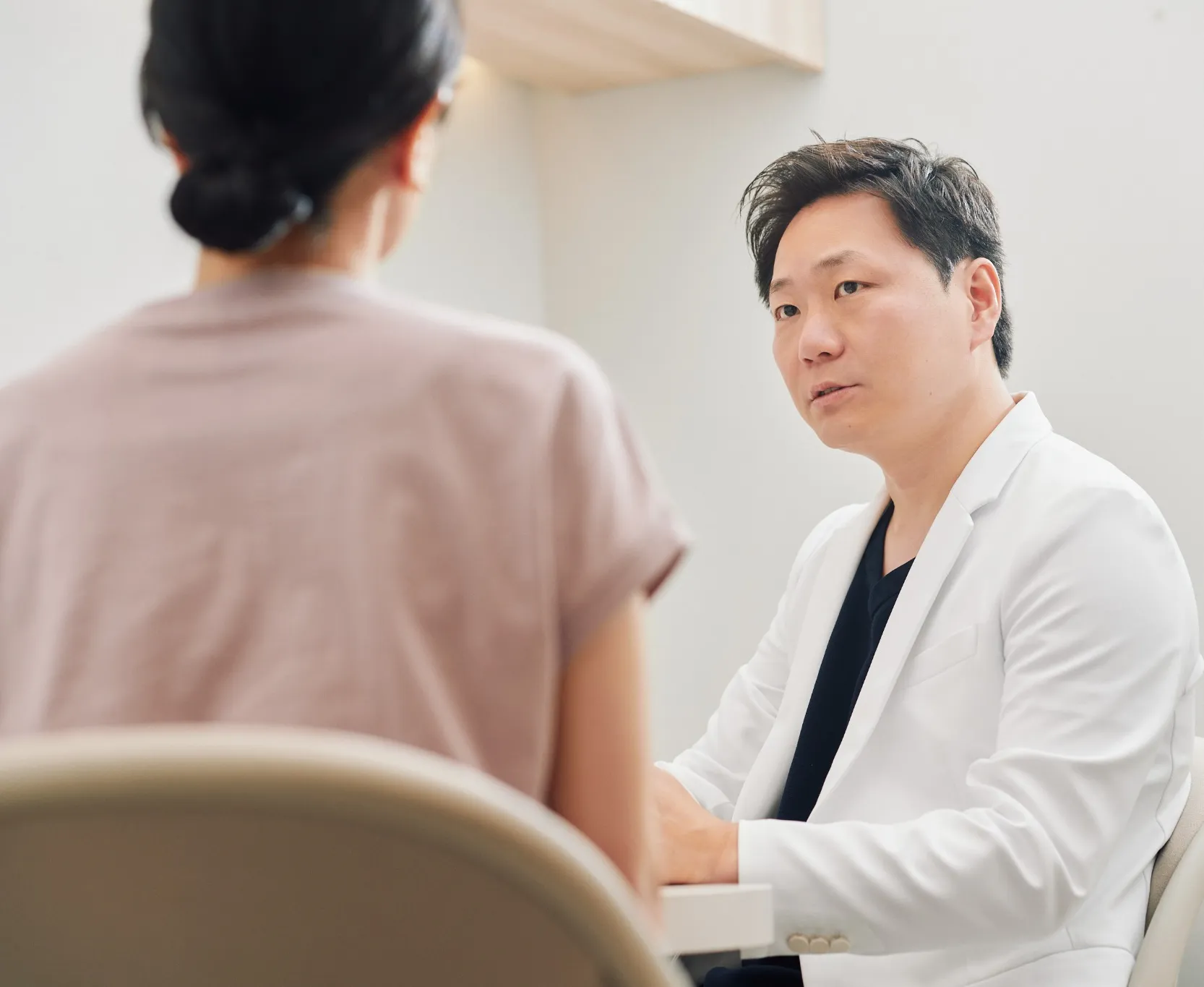 診察室で患者と向かい合って話す医師
