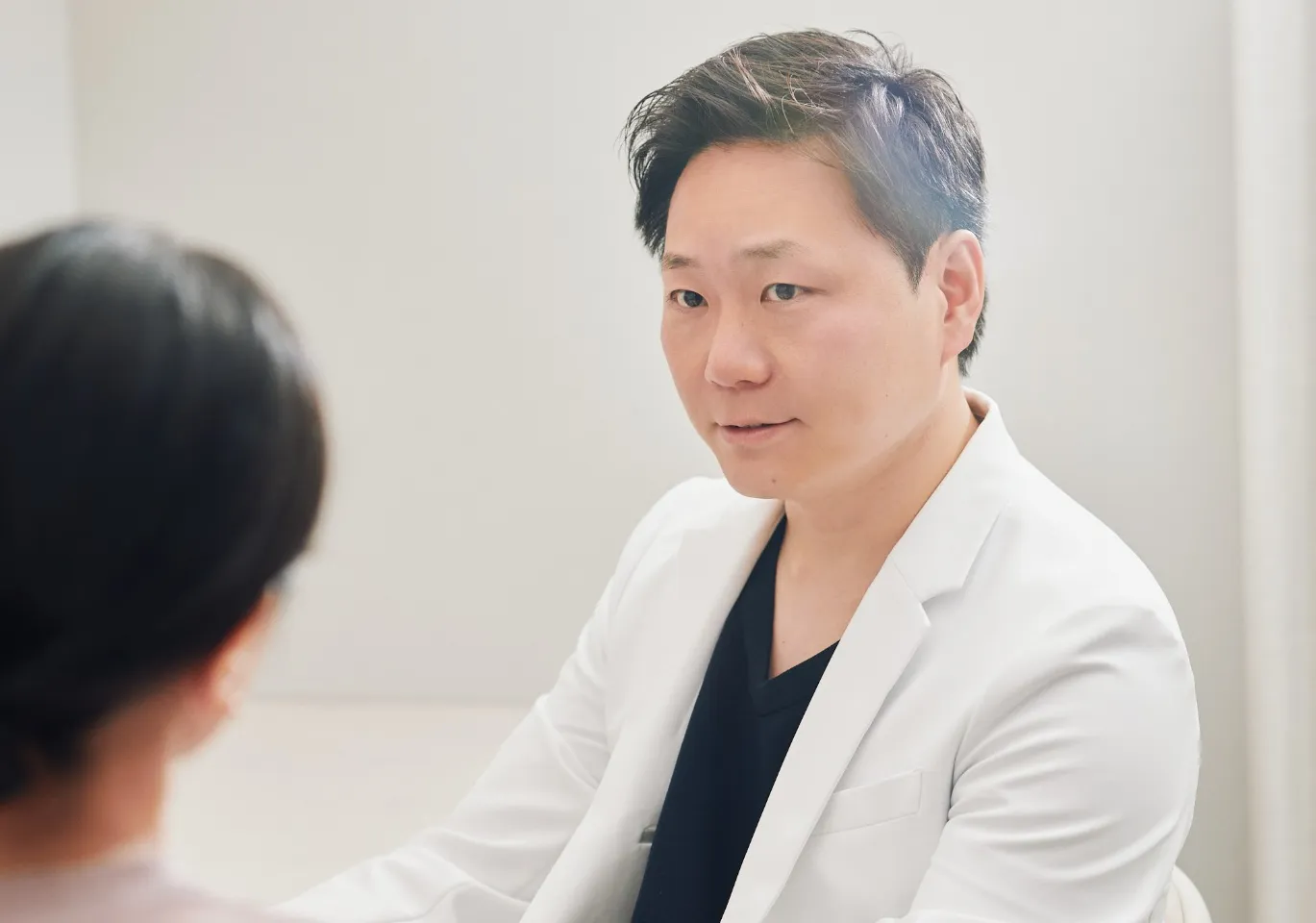 診察室で患者と向かい合って話す院長