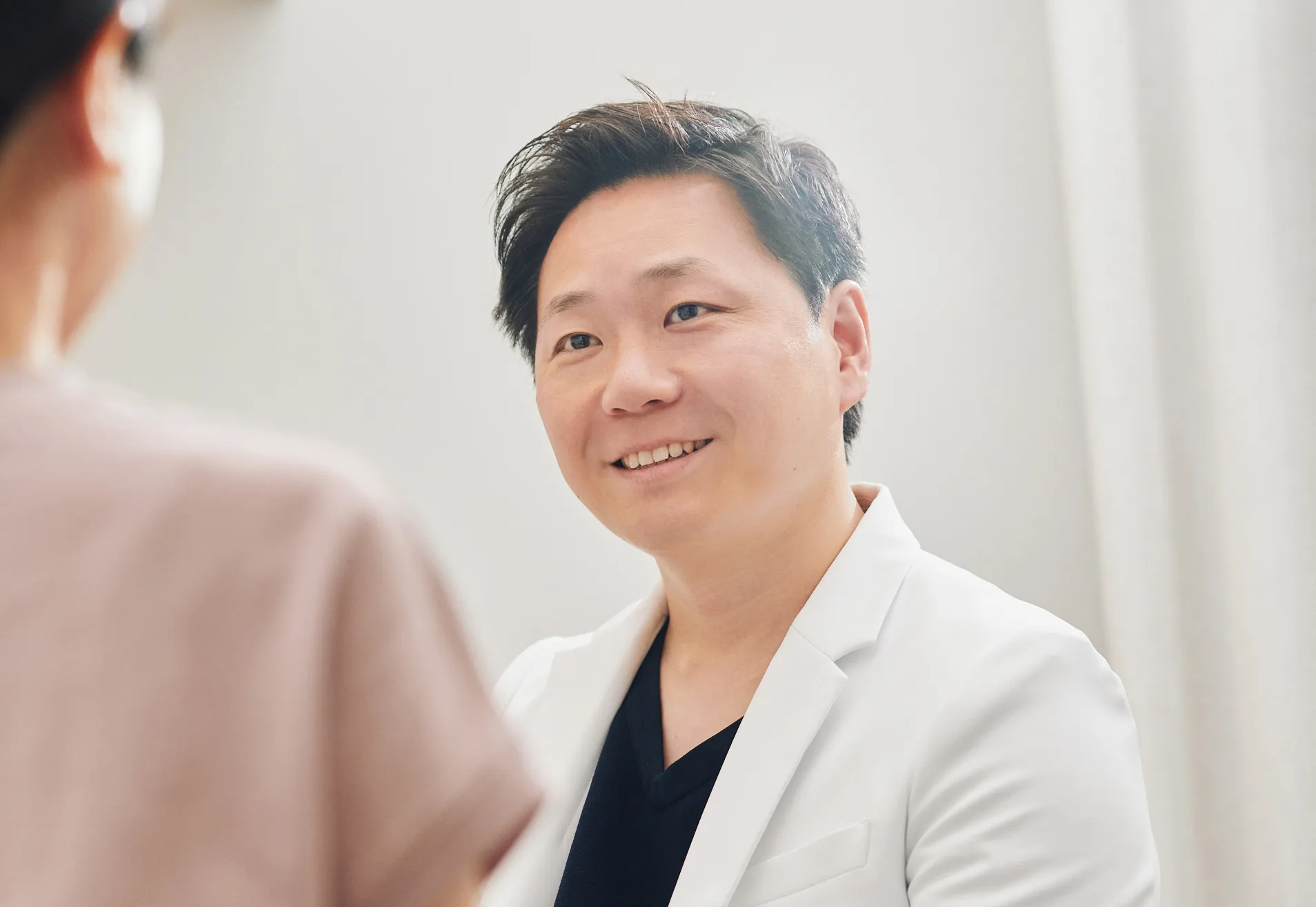 診察室で患者と向かい合って話す院長