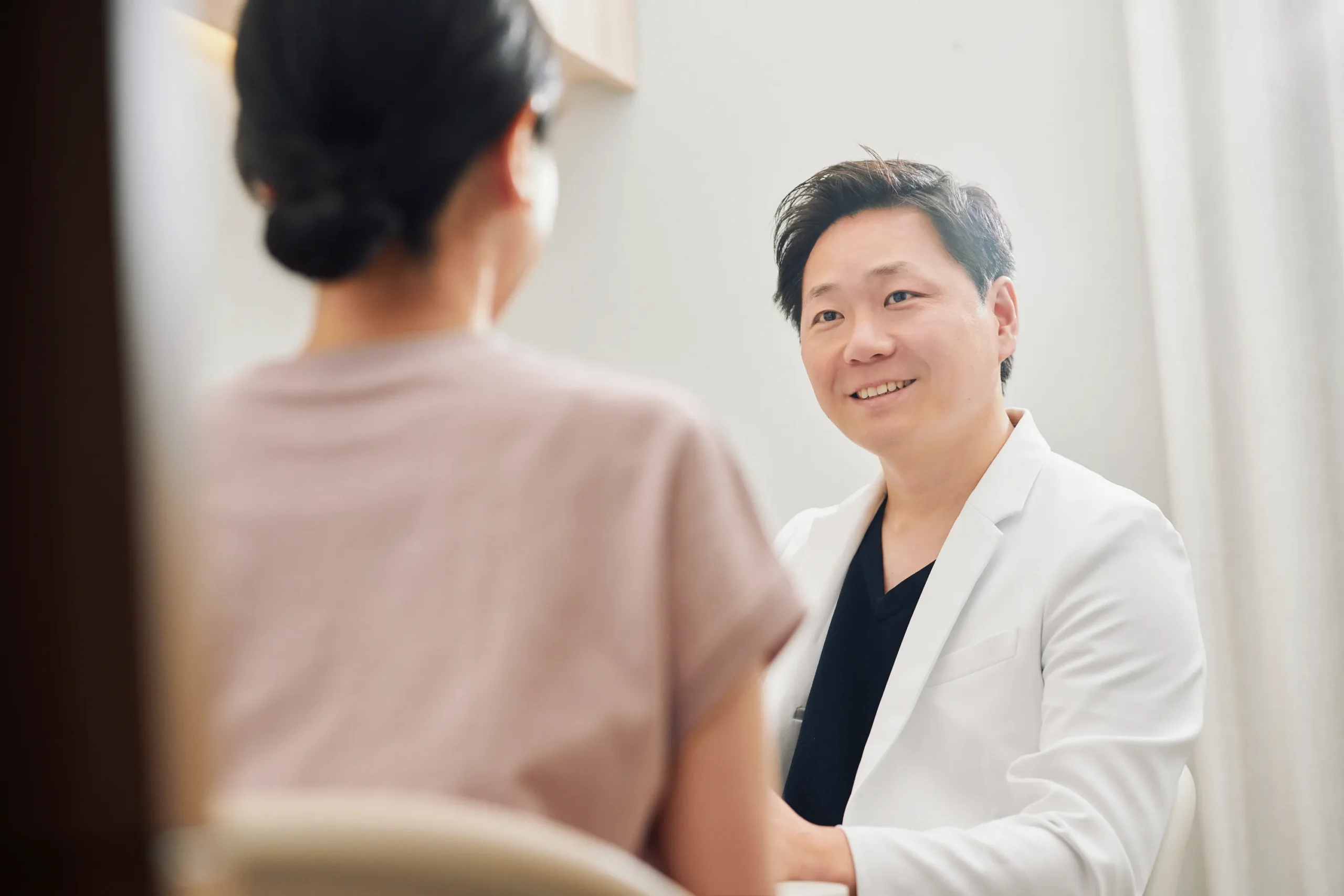 診察室で患者と向かい合って話す医師