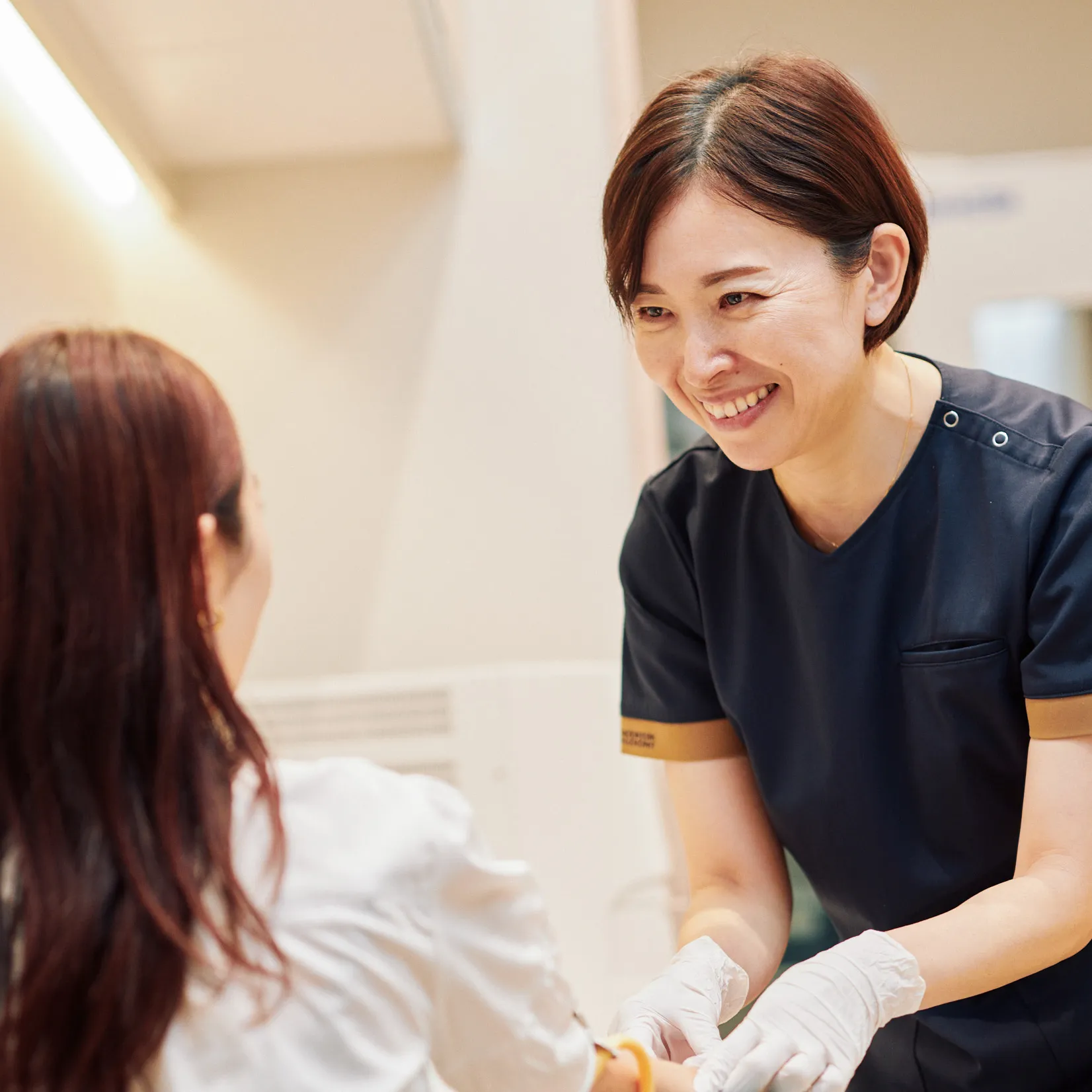 患者の腕に処置を行う看護師